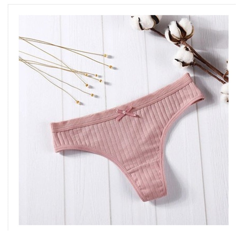  Women Panties in pink ribbed cotton with bow detail on a wooden background.