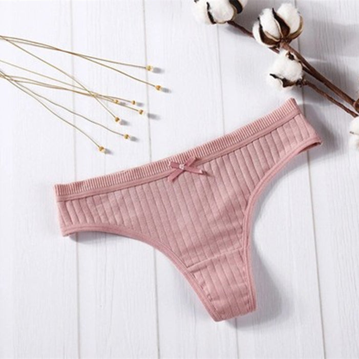 Women Panties in pink ribbed cotton with bow detail on a wooden background.